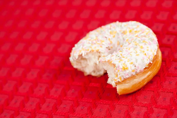 Halber Donut auf roter Tischdecke — Stockfoto