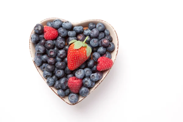 Különböző bogyók egy szív alakú tál — Stock Fotó