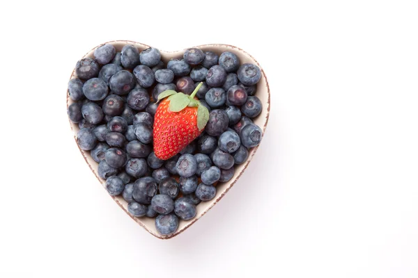 Blueberries and one Strawberry in a heart shaped bowl — ストック写真