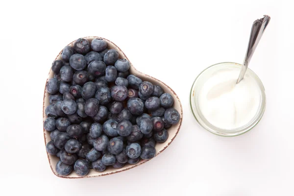 Yogur blanco y arándanos en un tazón en forma de corazón — Foto de Stock