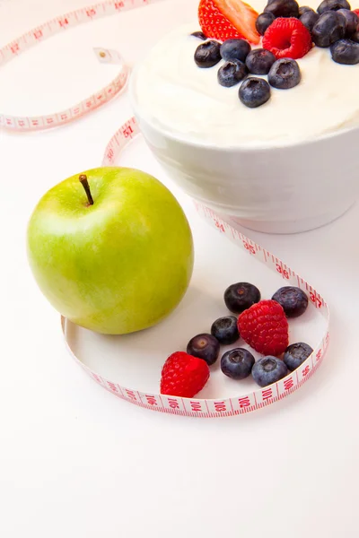 Apple and bowl of berries cream and a tape measure — Stock Photo, Image