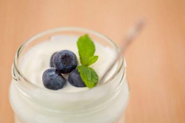 Närbild på en gryta med yoghurt med blåbär och blad — Stockfoto