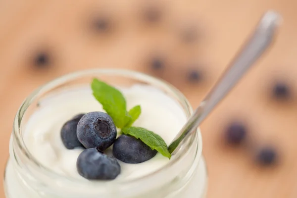 Nahaufnahme eines Topfes Joghurt mit vier Blättern und Blaubeeren — Stockfoto