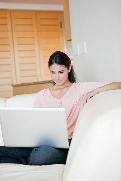 Mulher usando um laptop enquanto está sentado em um sofá — Fotografia de Stock