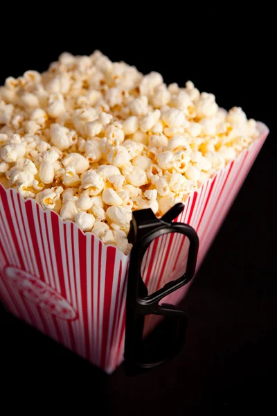 3D glasses hanging on the corner of a box of popcorn — Stock Photo, Image