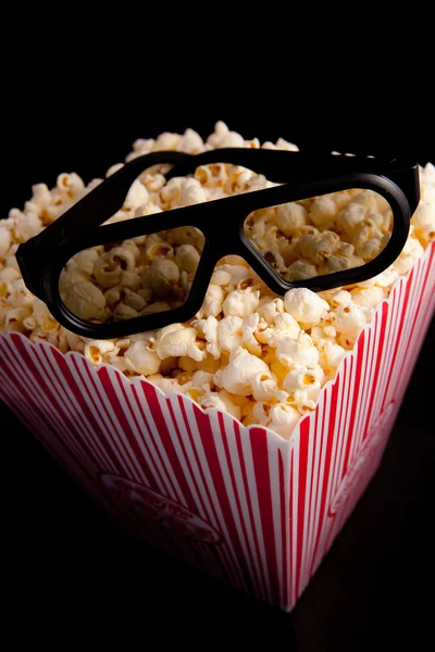 3D-glasögon ligger på toppen av en låda med popcorn — Stockfoto