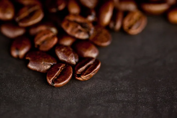 Dunkle, verschwommene Kaffeesamen, die zusammen auf einem schwarzen Tisch ausgelegt sind — Stockfoto