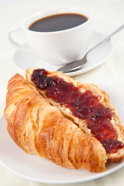 Coffee cup behind a croissant — Stock Photo, Image