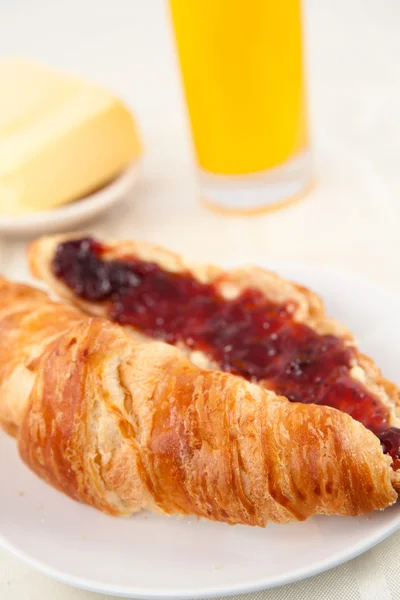 Croissant na frente de um copo de suco de laranja — Fotografia de Stock