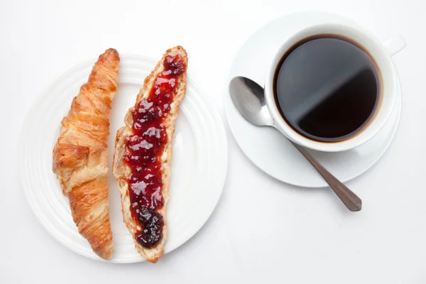 Taza de café colocada junto a un croissant — Foto de Stock