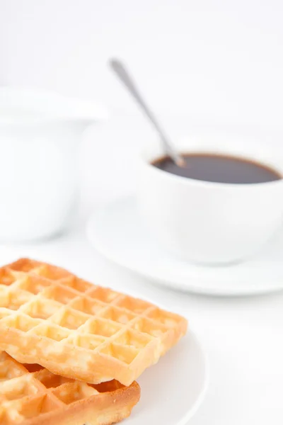 Waffles and a cup of coffee with a spoon on white plates and mil — Stock Photo, Image