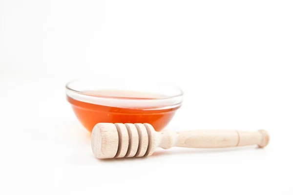 Honey bowl behind a honey dipper — Stock Photo, Image