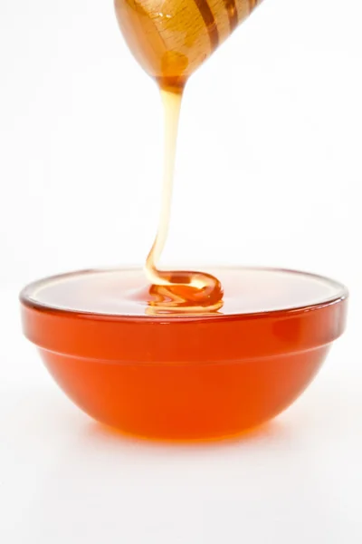 Honey trickle dropping in full honey bowl — Stock Photo, Image