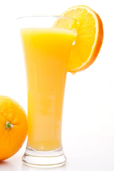 Стакан апельсинового сока рядом с апельсином — стоковое фото