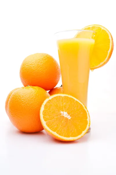 Montón de naranjas cerca de un vaso de jugo de naranja — Foto de Stock