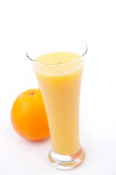 Orange derrière un grand verre de jus d'orange — Photo