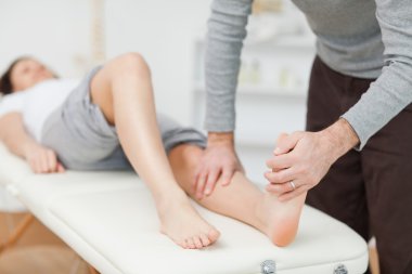 Physiotherapist stretching a barefoot clipart