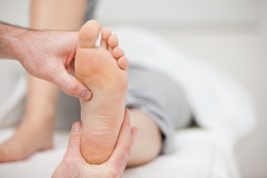 Doctor holding the foot of a woman clipart