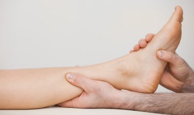 Chiropodist holding the ankle of a patient clipart