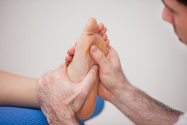 Podiatrist practicing reflexology on the foot of woman clipart