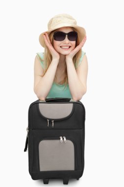 Cheerful woman leaning on a suitcase while sitting clipart
