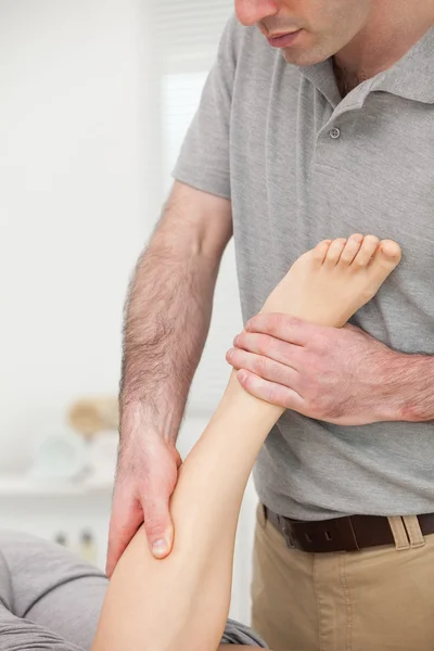 Arzt massiert einer Frau im Liegen das Bein — Stockfoto