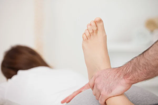 Vrouw liggen vooruit terwijl een fysio haar voet manipuleert — Stockfoto