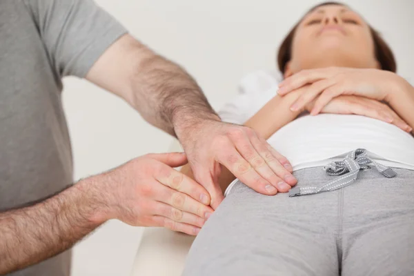 Mulher deitada enquanto um fisioterapeuta massageia a coxa — Fotografia de Stock