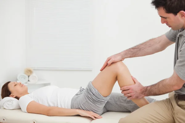 Woman lying while a man manipulating her leg — Stock Photo, Image