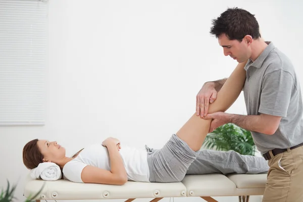 Physiotherapist massaging a leg while placing it on his shoulder — Stock Photo, Image