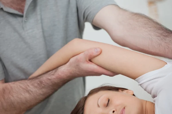 Osteopath hält den Arm einer Frau, während er ihren Körper massiert — Stockfoto