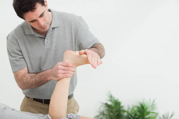 Brown-haired therapist stretching the foot of a patient — Stock Photo, Image