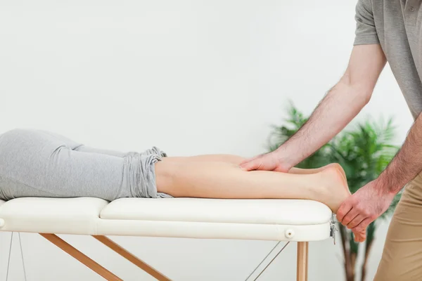 Donna sdraiata mentre un massaggiatore massaggia i polpacci — Foto Stock