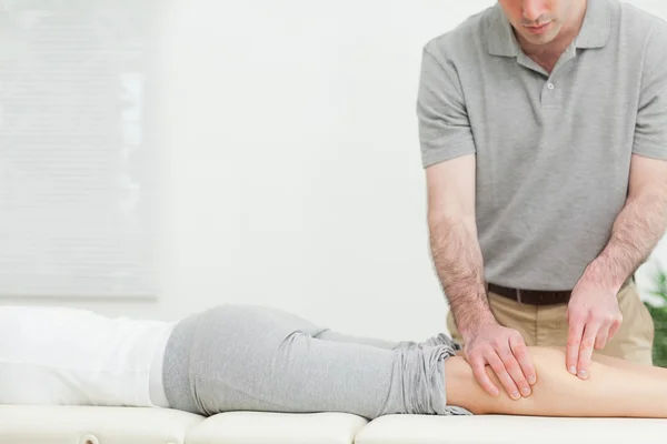 Mulher deitada para a frente enquanto um fisioterapeuta massageia a perna — Fotografia de Stock