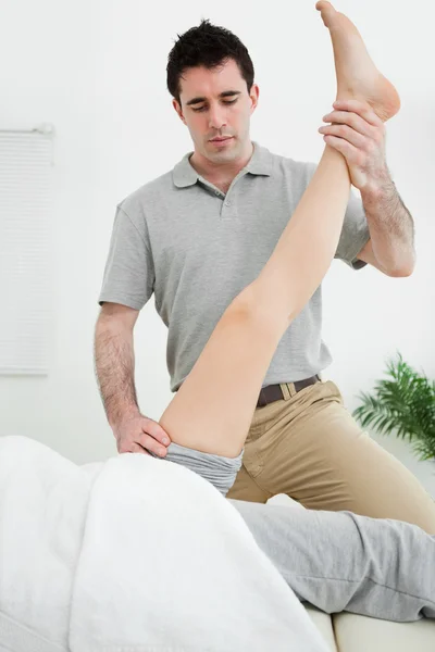 Physiotherapist raising the leg of a patient — Stock Photo, Image