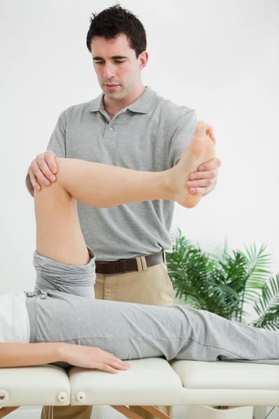 Brünette Physiotherapeutin manipuliert ein Bein — Stockfoto