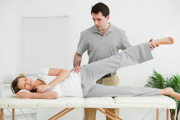 Serious practitioner rising the leg of his patient — Stock Photo, Image