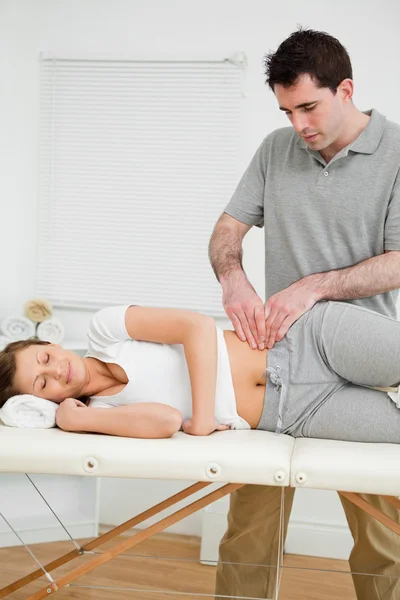 Serious physiotherapist checking the pelvis of a woman — Stock Photo, Image