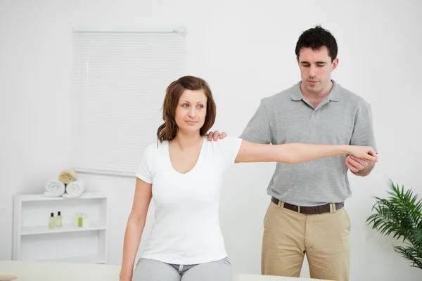 Serious practitioner extending the arm of a patient — Stock Photo, Image