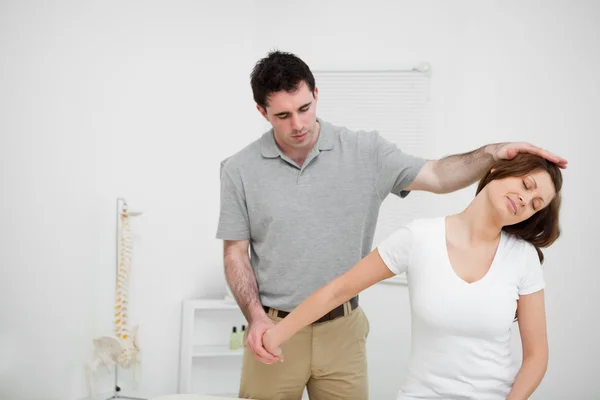 Osteopath stretching the arm of a woman — Stock Photo, Image