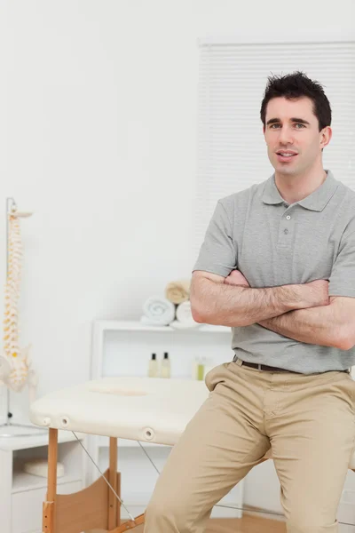 Rauhallinen osteopaatti istuu kädet ristissä. — kuvapankkivalokuva