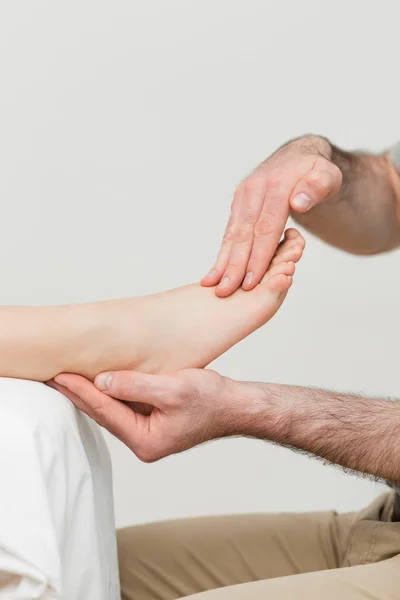 Praticante segurando o pé de um paciente — Fotografia de Stock