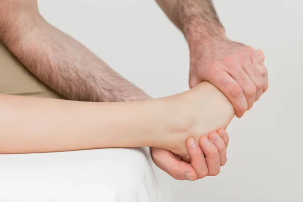 Osteopat hålla bollen på foten av en patient — Stockfoto