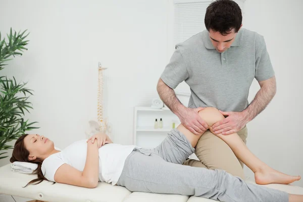 Black-haired osteopath touching the knee of a patient — Stock Photo, Image