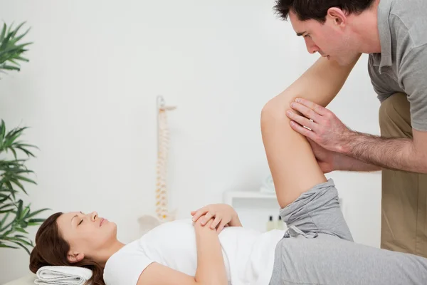 Ernstige fysiotherapeut verhogen een been — Stockfoto