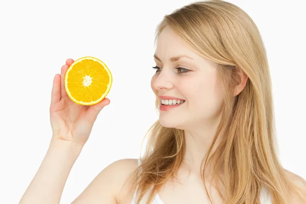 Joyful woman presenting an orange while looking at it — Stock Photo, Image