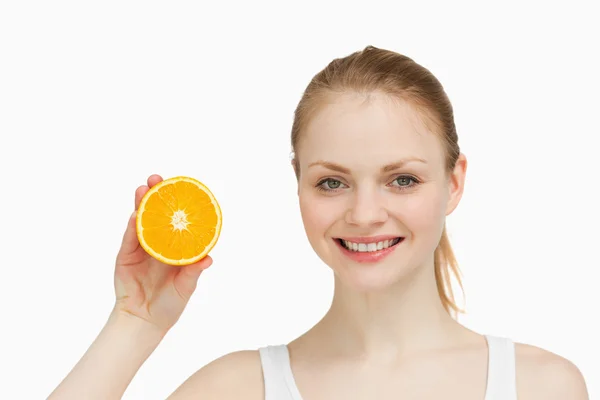 Mulher alegre apresentando uma laranja — Fotografia de Stock
