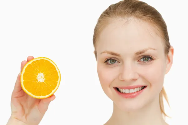 Close-up de uma mulher alegre apresentando uma laranja — Fotografia de Stock