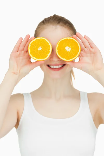 Mujer alegre poniendo naranjas en sus ojos — Foto de Stock