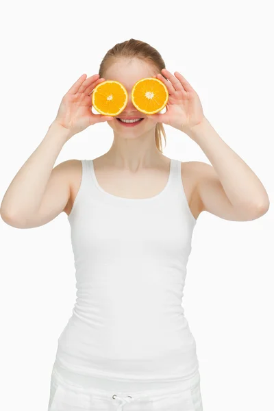 Joyful woman placing oranges on her eyes — Stock Photo, Image